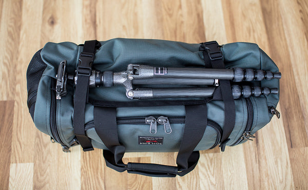 The Road Buddy Lash Straps holding a camera tri-pod on a Road Buddy Duffel 60.